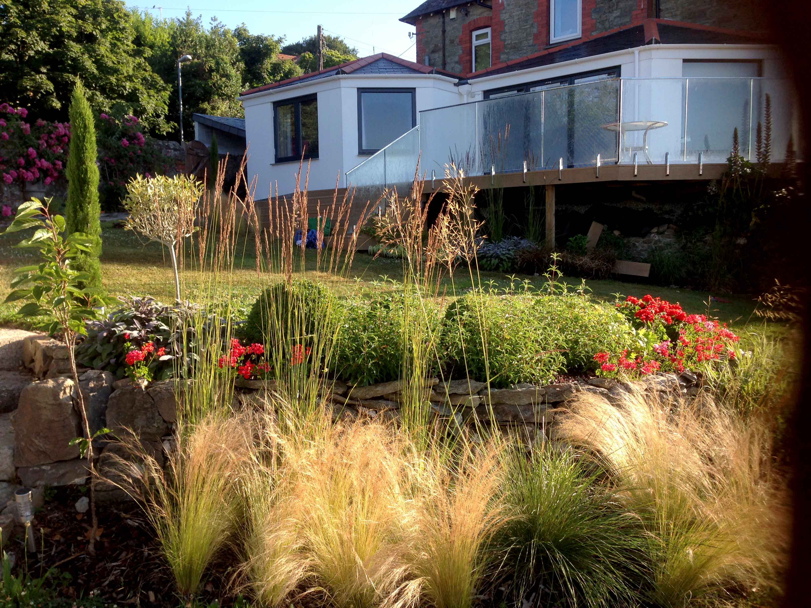 view of grasses and sloping lawn back to decking and house